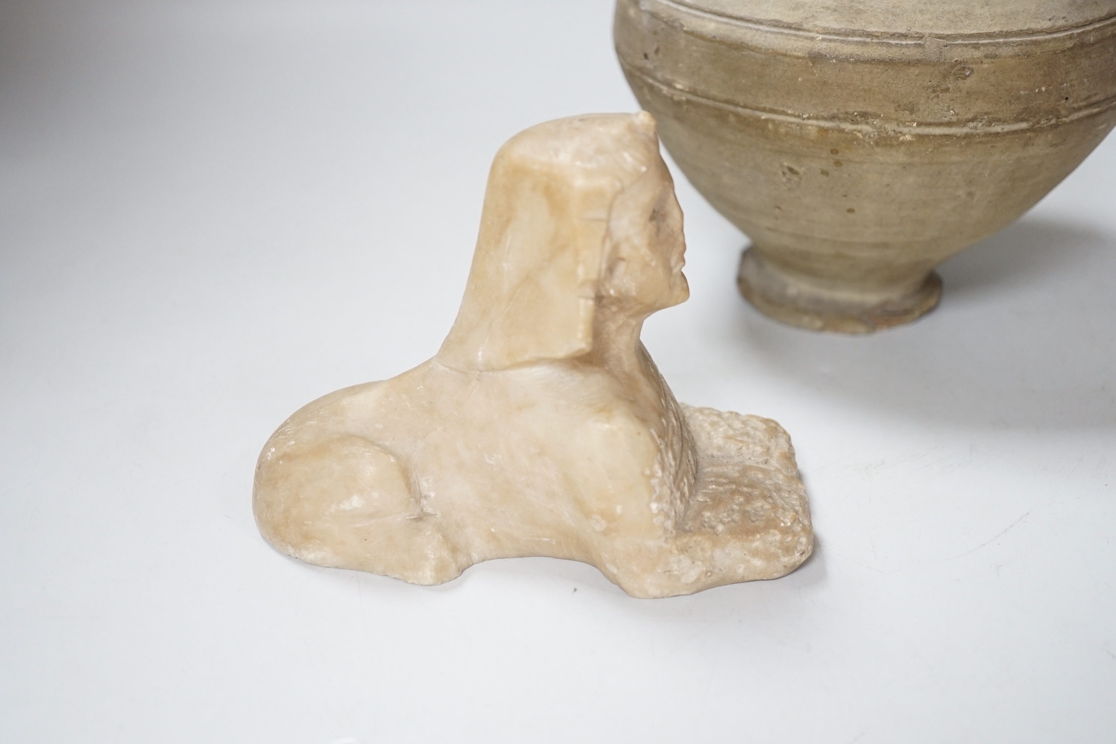 An Egyptian style alabaster model of a sphinx and a twin handled pottery vase, the largest 25cm high